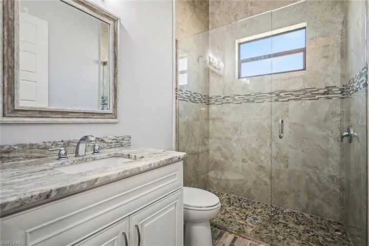 Bathroom featuring a stall shower, vanity, and dark wood-type flooring