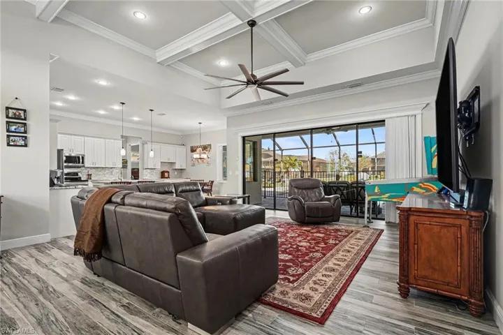 Living area featuring crown molding, recessed lighting, coffered ceiling, ceiling fan, and light wood finished floors