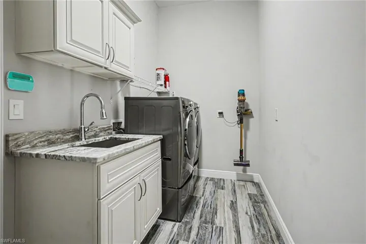 Laundry room with cabinet space, light wood-style flooring, and washing machine and clothes dryer