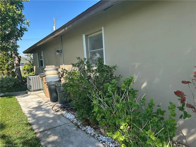 View of side of home with sidewalk and central AC
