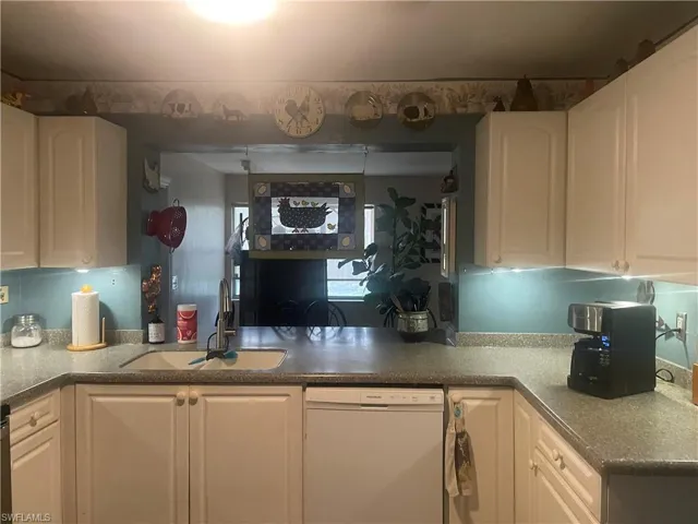 Kitchen featuring white cabinets, a sink, and white dishwasher