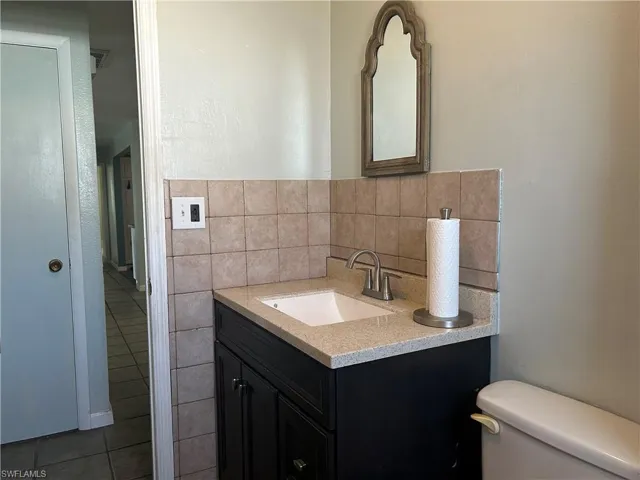 Guest bathroom  featuring updated vanity, tile walls, tile patterned floors, and toilet