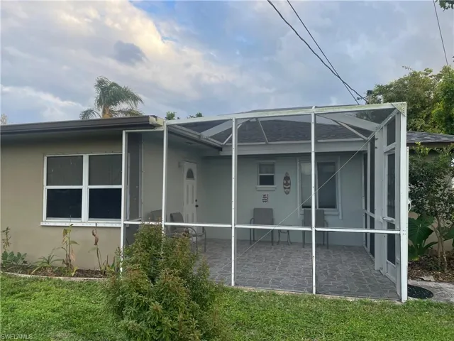 Back of property with a lawn, a patio, and glass enclosure