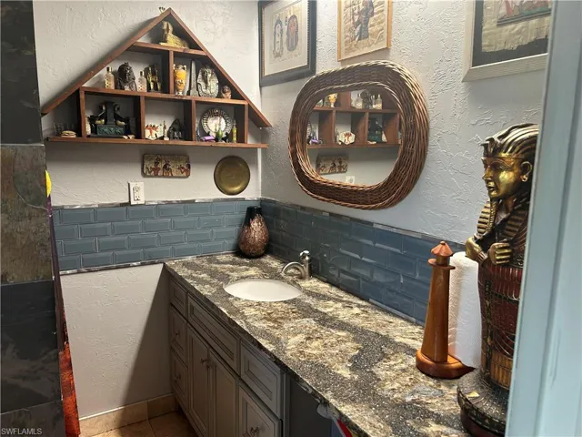 Primary bathroom granite counters, featuring tasteful backsplash and vanity
