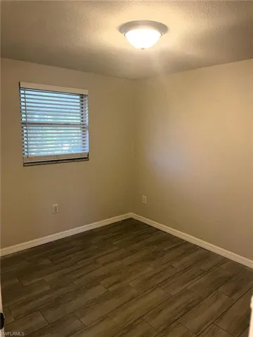 Spare room with dark wood-type flooring and a textured ceiling