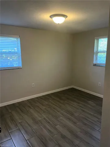 Empty room featuring healthy amount of natural light, wood tiled floors, and a textured ceiling