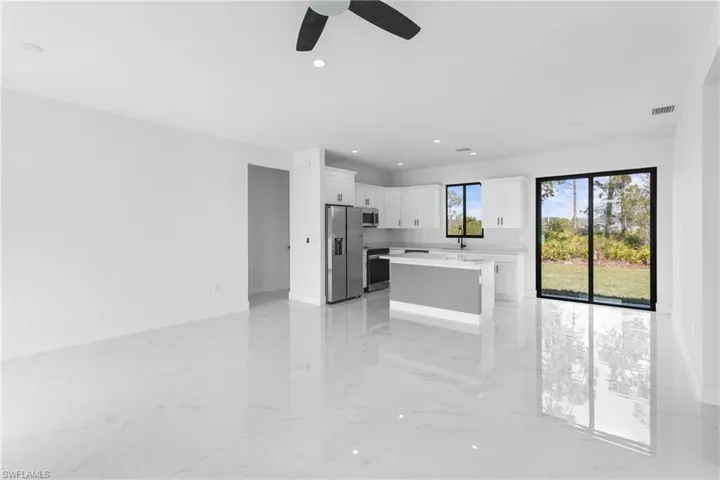 Kitchen with white cabinetry, a kitchen island, ceiling fan, and appliances with stainless steel finishes