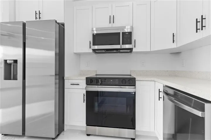 Kitchen with white cabinetry and appliances with stainless steel finishes