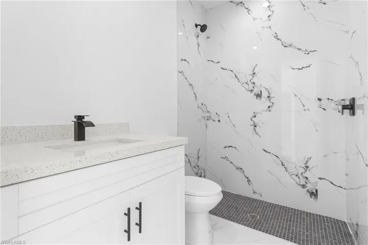Bathroom featuring tiled shower, vanity, and toilet