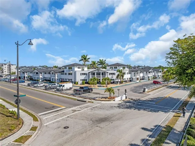 View of asphalt street featuring a residential view, sidewalks, street lights, and curbs