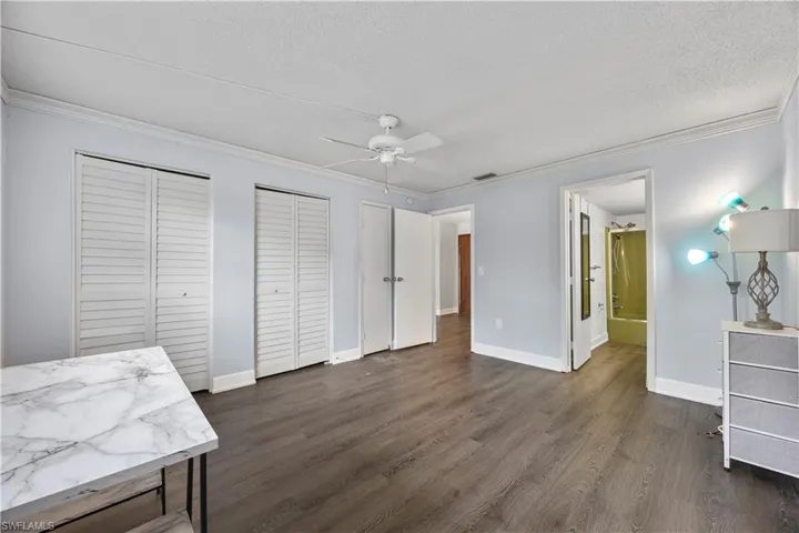 Unfurnished bedroom with multiple closets, crown molding and vinyl flooring.
