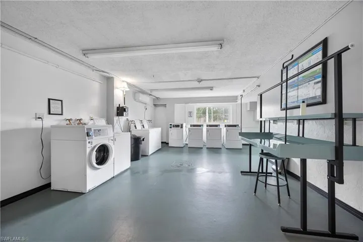 Community laundry featuring washing machine and dryer and a textured ceiling