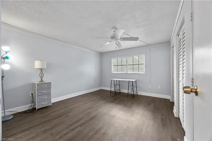 Bedroom with crown molding, ceiling fan, and vinyl floor.