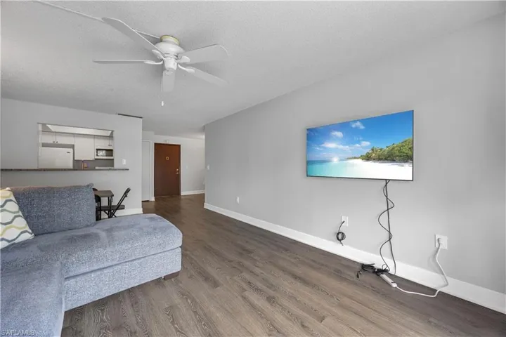 Living room with ceiling fan, and vinyl flooring.