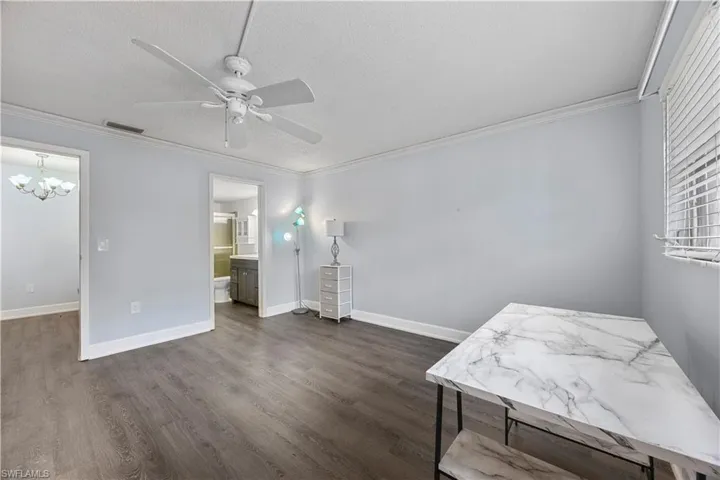 Bedroom with crown molding, ceiling fan, and vinyl flooring.