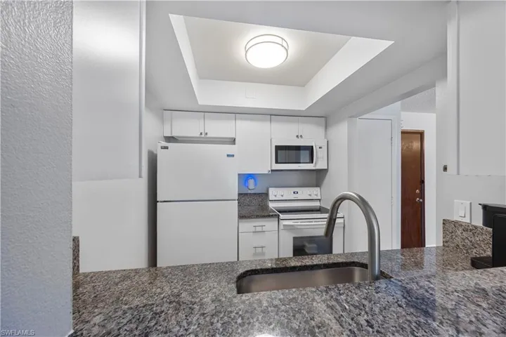 Kitchen with granite countertops, white cabinets and appliances.