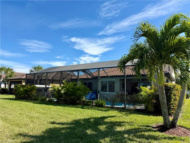 Rear view of property with a lanai, a sunroom, a lawn, and stucco siding