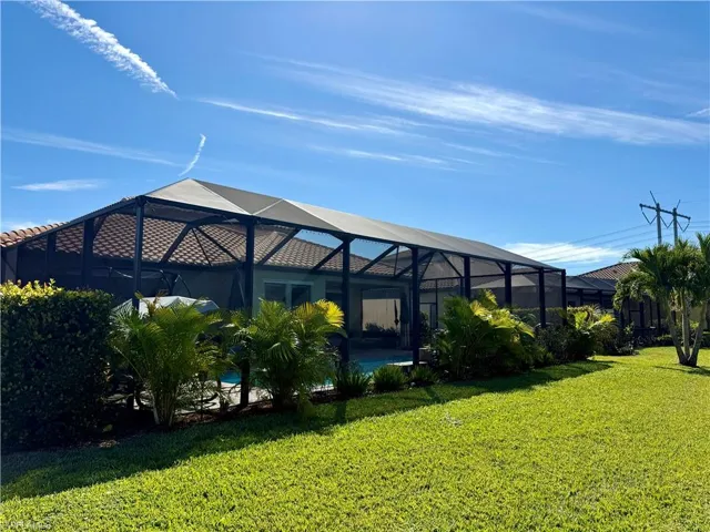 View of green lawn with a sunroom and glass enclosure
