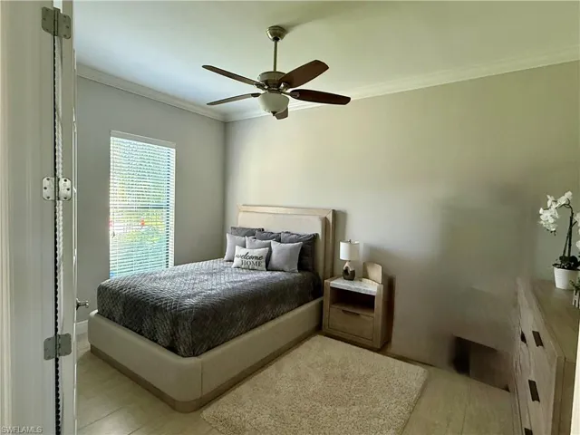 Den used as guest bedroom crown molding, a ceiling fan, and light wood finished floors