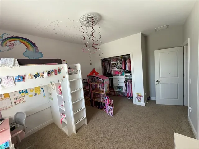 Bedroom with light colored carpet and a chandelier