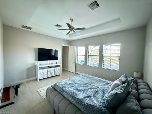 Bedroom featuring a tray ceiling, wood finished floors, and ceiling fan