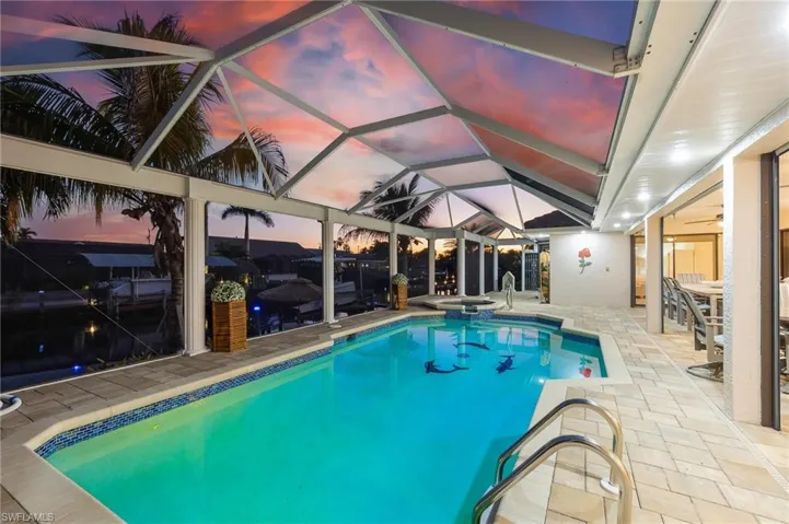View of pool featuring glass enclosure, a patio, a sunroom, and a pool with connected hot tub