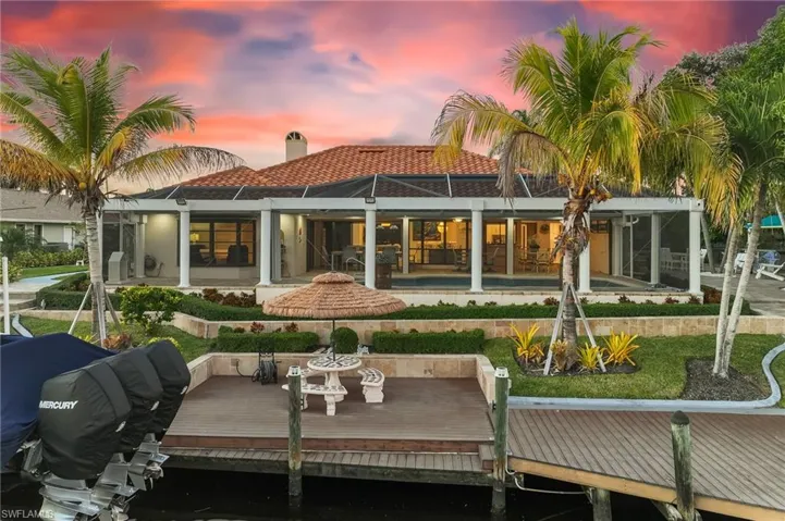 Back of property at dusk with a sunroom, a chimney, and a lanai