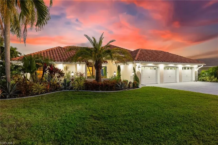 Mediterranean / spanish-style home with driveway, stucco siding, a front yard, and a tile roof