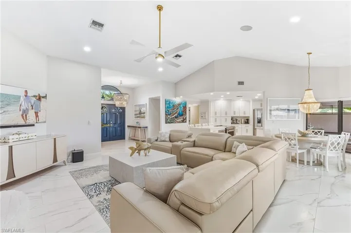 Living area featuring a ceiling fan, a chandelier, recessed lighting, light marble finish floors, and high vaulted ceiling