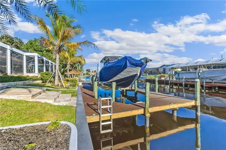 Dock with boat lift, a sunroom, and a water view