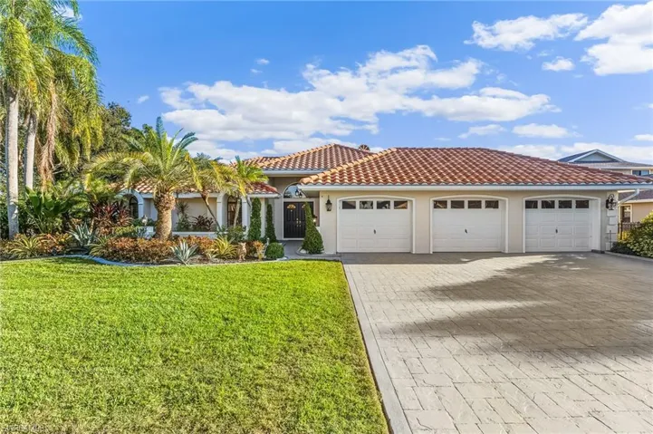 Mediterranean / spanish-style home featuring decorative driveway, stucco siding, an attached garage, a front lawn, and a tile roof