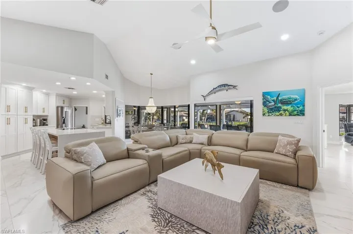 Living area featuring light marble finish floors, recessed lighting, a ceiling fan, high vaulted ceiling, and healthy amount of natural light