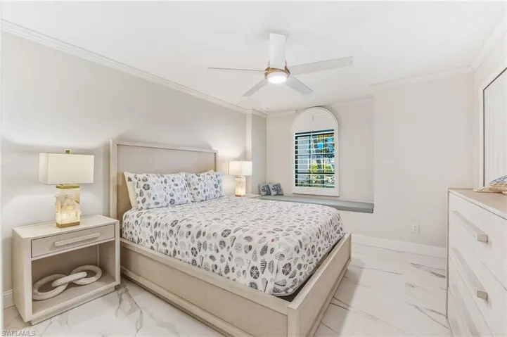 Bedroom featuring light marble finish flooring, ornamental molding, and a ceiling fan