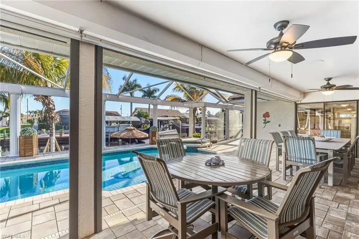 View of patio / terrace with outdoor dining space, glass enclosure, an outdoor pool, and a ceiling fan