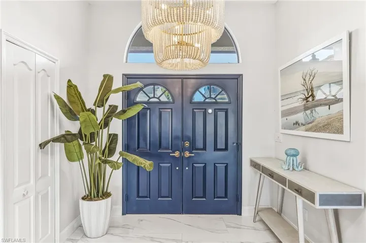 Foyer featuring marble look tile flooring and a chandelier