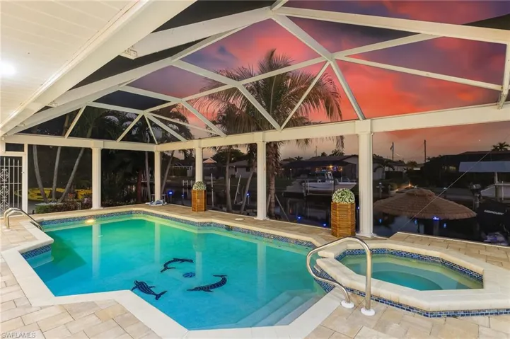 Swimming pool with glass enclosure, a patio area, a sunroom, and an in-ground hot tub