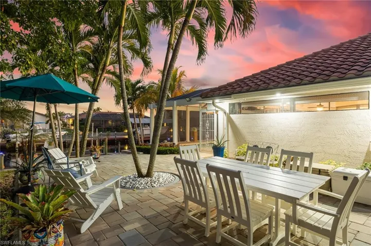 Patio terrace at dusk featuring outdoor dining space, a patio, and a water view