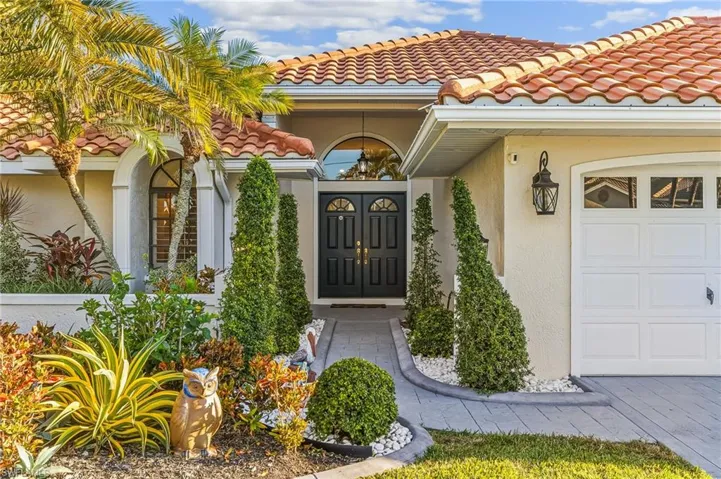 Entrance to property featuring stucco siding, a tiled roof, and an attached garage