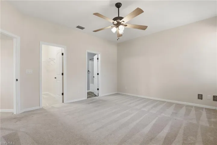 Unfurnished bedroom featuring a spacious closet, ceiling fan, and light carpet