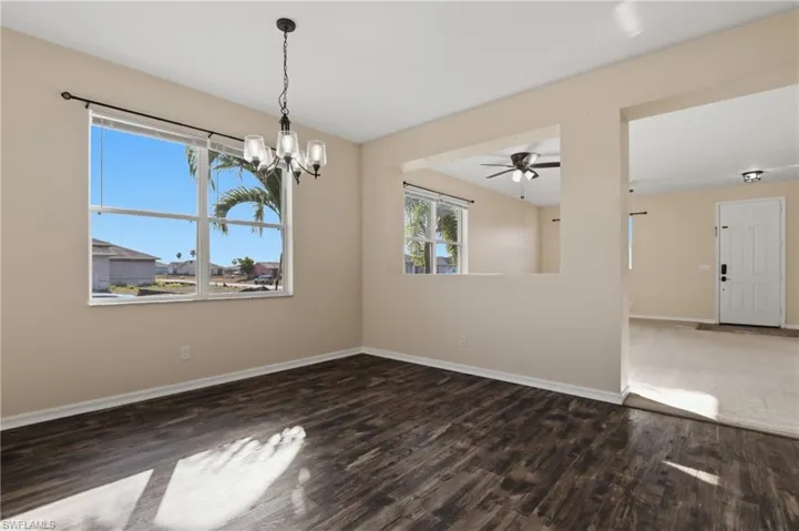 Unfurnished room with dark wood-style floors, ceiling fan, and a chandelier