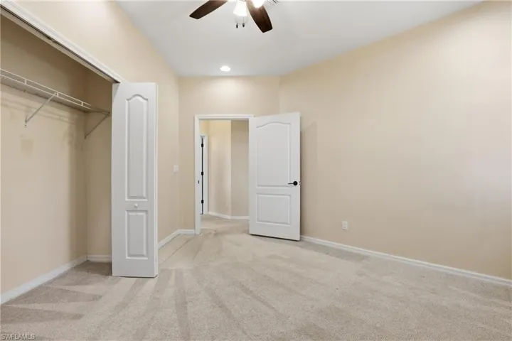 Unfurnished bedroom with light colored carpet, a closet, and a ceiling fan