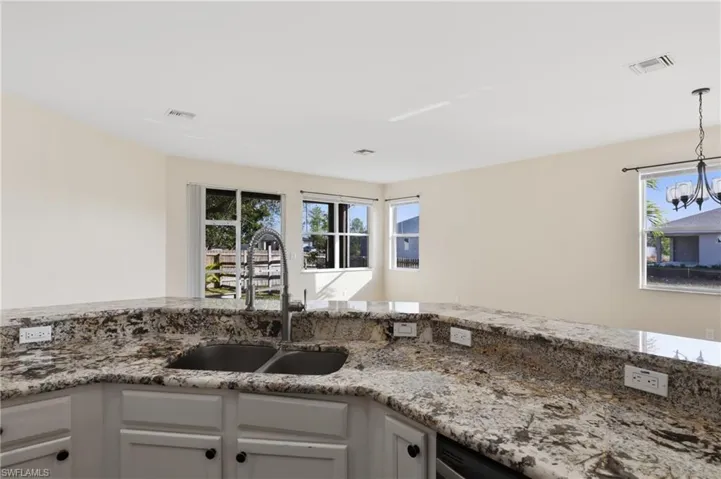 Kitchen with light stone countertops, white cabinets, and decorative light fixtures