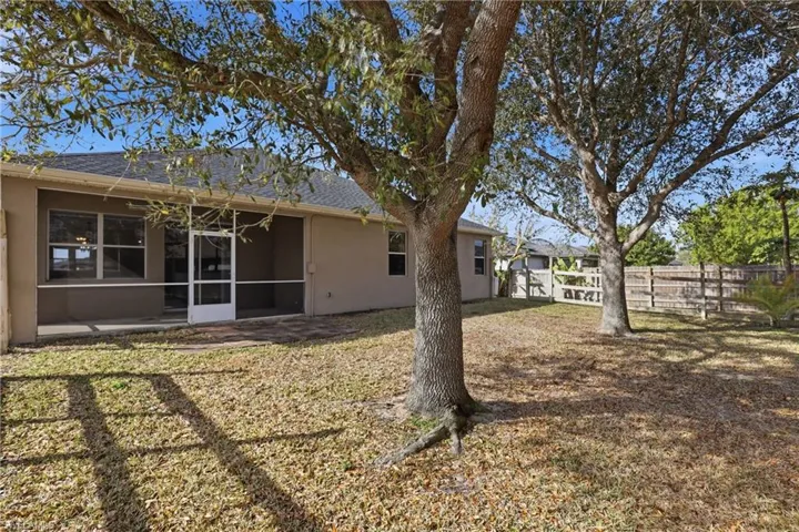 Back of property featuring stucco siding, a fenced backyard, roof with shingles, and a sunroom