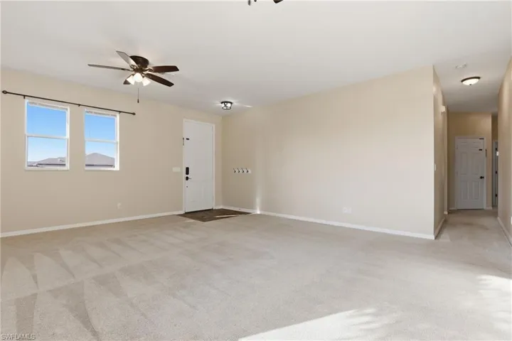 Unfurnished room featuring light carpet and a ceiling fan