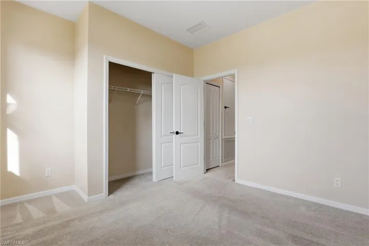 Unfurnished bedroom featuring light carpet and a closet
