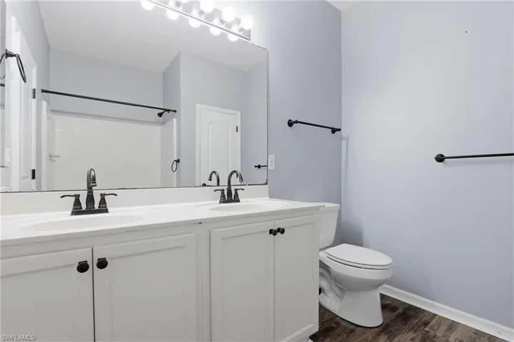 Bathroom with double vanity and dark wood-type flooring