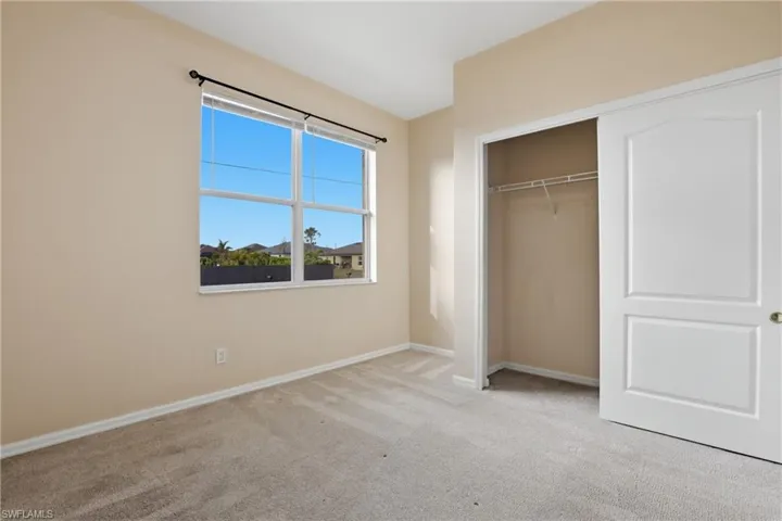 Unfurnished bedroom with light colored carpet and a closet