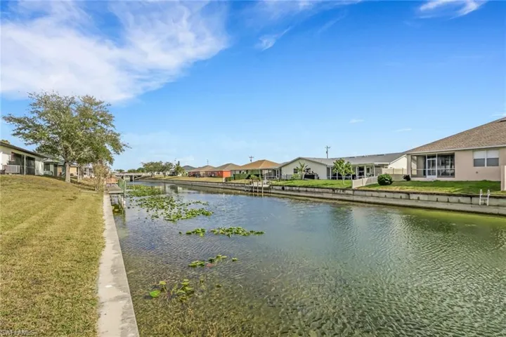 View of green lawn with a residential view, a water view, and a patio area