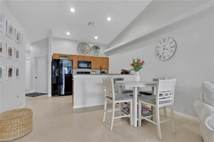 Kitchen with black appliances, vaulted ceiling, light stone countertops, a peninsula, and recessed lighting