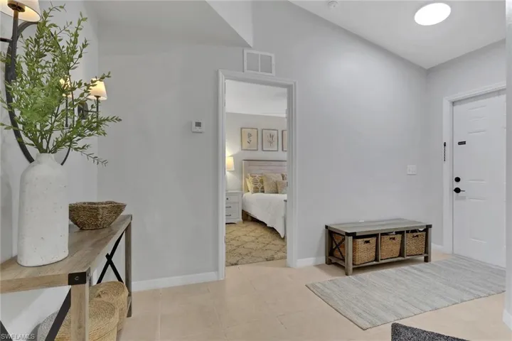 Living area with lofted ceiling, light tile patterned floors, and ceiling fan